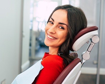 Woman in dental chair leaning back and smiling