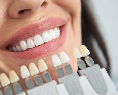 Cosmetic dentist holding shade guide next to smile of dental patient