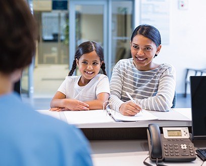 Mother and daughter at dental office reception desk