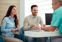 Dental team member and two patients discussing the cost of cosmetic dentistry in Fort Worth