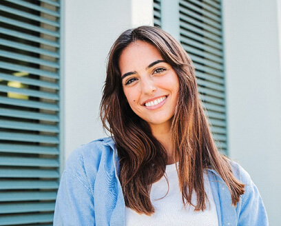 woman with white teeth smiling while standing outsite 