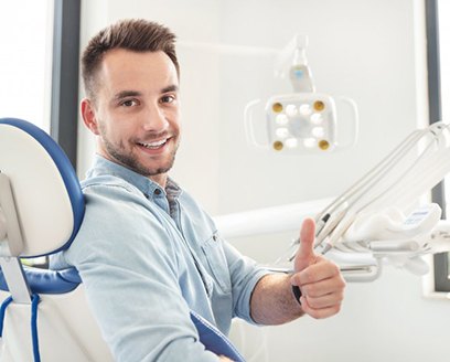 Smiling man giving thumbs up in dental treatment chair