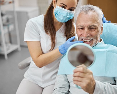 man smiling while looking in dental mirror 