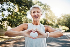 Smiling lady makes shape of heart with her hands