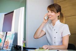 Receptionist on phone discussing how to pay for emergency dental care in Fort Worth