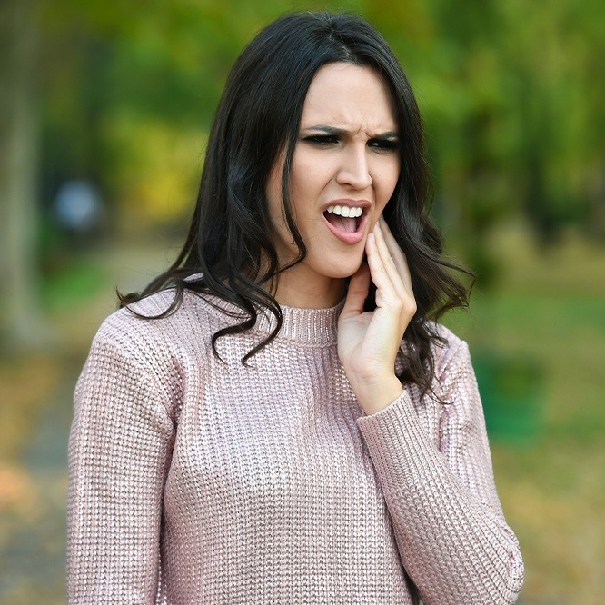 Grimacing woman holding her cheek in pain