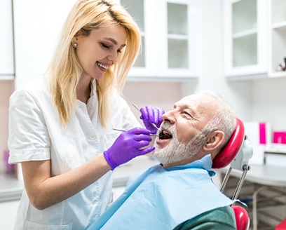 An older man having his smile and dental implants checked at the dentist’s office