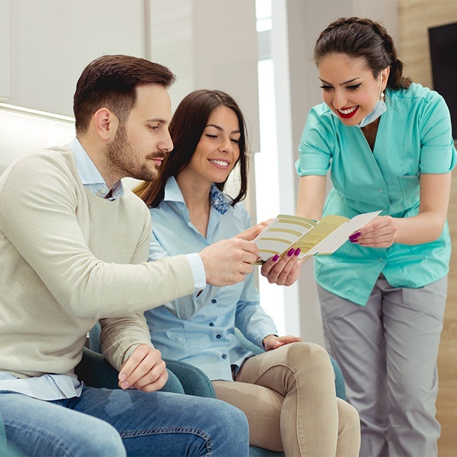 Man and woman talking to dental team member about dental insurance in Fort Worth