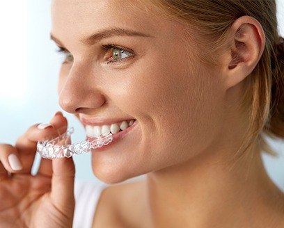 Woman placing Invisalign tray in her mouth