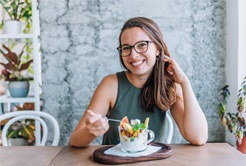 Woman smiling while eating healthy breakfast at home