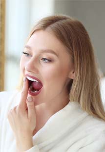 Woman looking at her gums in handheld mirror