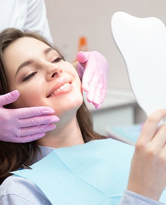 Woman in purple dental chair admiring reflection in mirror