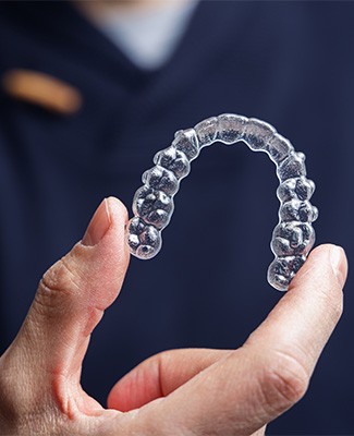 Dentist in navy blue scrubs holding Invisalign