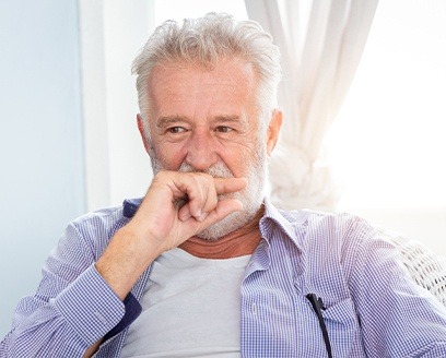 Older man covering his smile with his hand