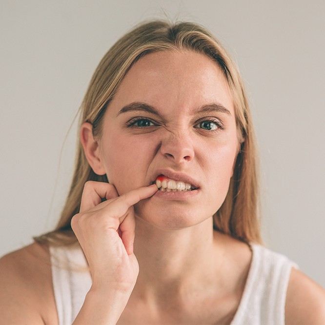 Woman pointing to her red gums that need gum disease treatment in Fort Worth