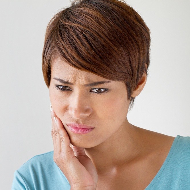 Woman holding her cheek in pain needing root canal treatment in Fort Worth