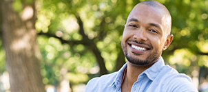 Man in denim shirt smiling outdoors