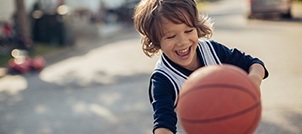 Child playing basketball with healthy smile thanks to children's dentistry
