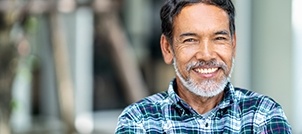 Older man in blue plaid shirt smiling