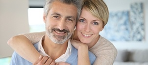 Man and woman smiling and holding each other in living room