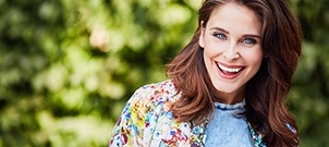 Woman in floral blouse grinning outdoors