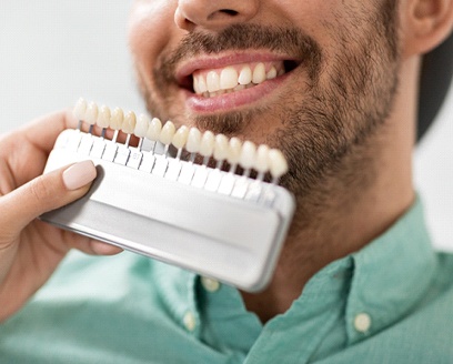 Cosmetic dentist color matching veneers to the teeth of a patient