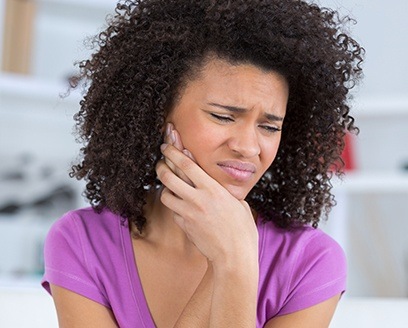 Woman in pain holding cheek before wisdom tooth extraction