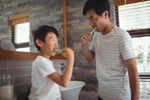 parent and child brushing their teeth in a bathroom