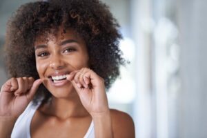 Young woman flossing her teeth.