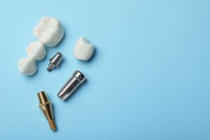Dental bridge, crown, and implant posts on light blue surface