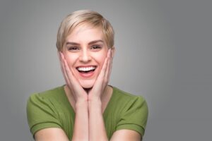 Joyous woman smiling and holding hands to her face.